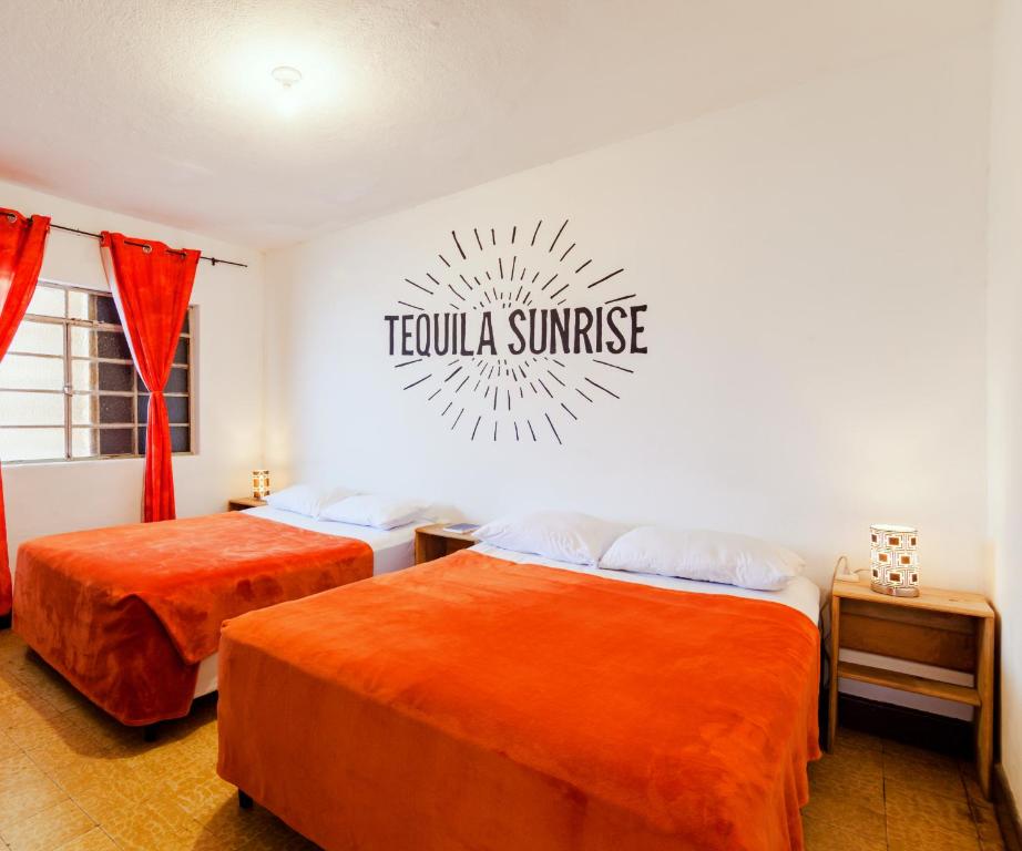 two beds in a room with a sign on the wall at Tequila Sunrise Hostel in Guatemala