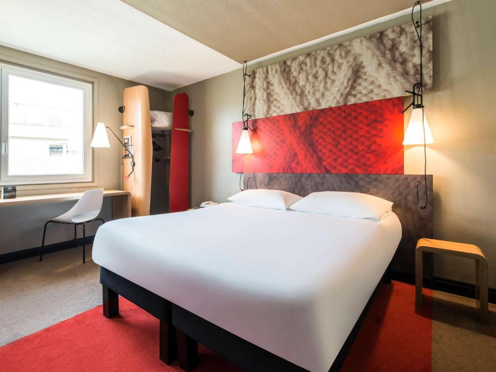 um quarto com uma grande cama branca e uma secretária em Hôtel Ibis Cognac Centre em Cognac