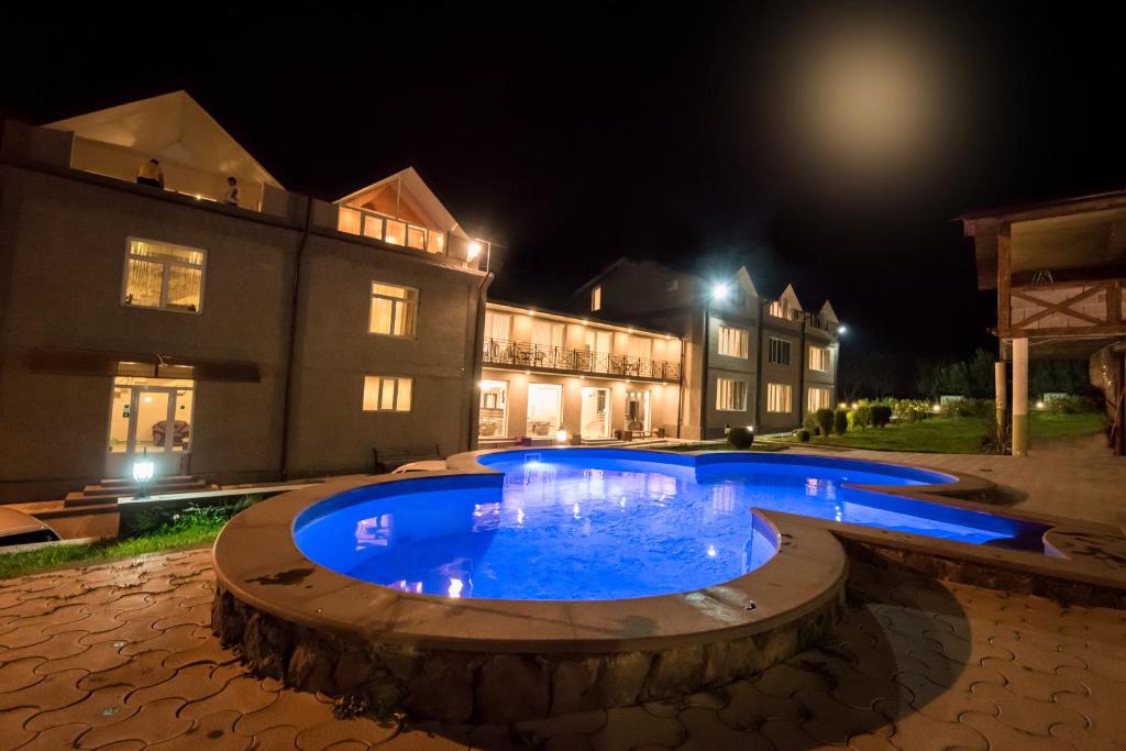 duży niebieski basen przed budynkiem w nocy w obiekcie Laguna Hotel w mieście Wanadzor