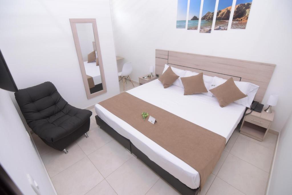 ein Schlafzimmer mit einem Bett mit einem Stuhl und einem Spiegel in der Unterkunft BLH Business Loft Hotel in Bucaramanga
