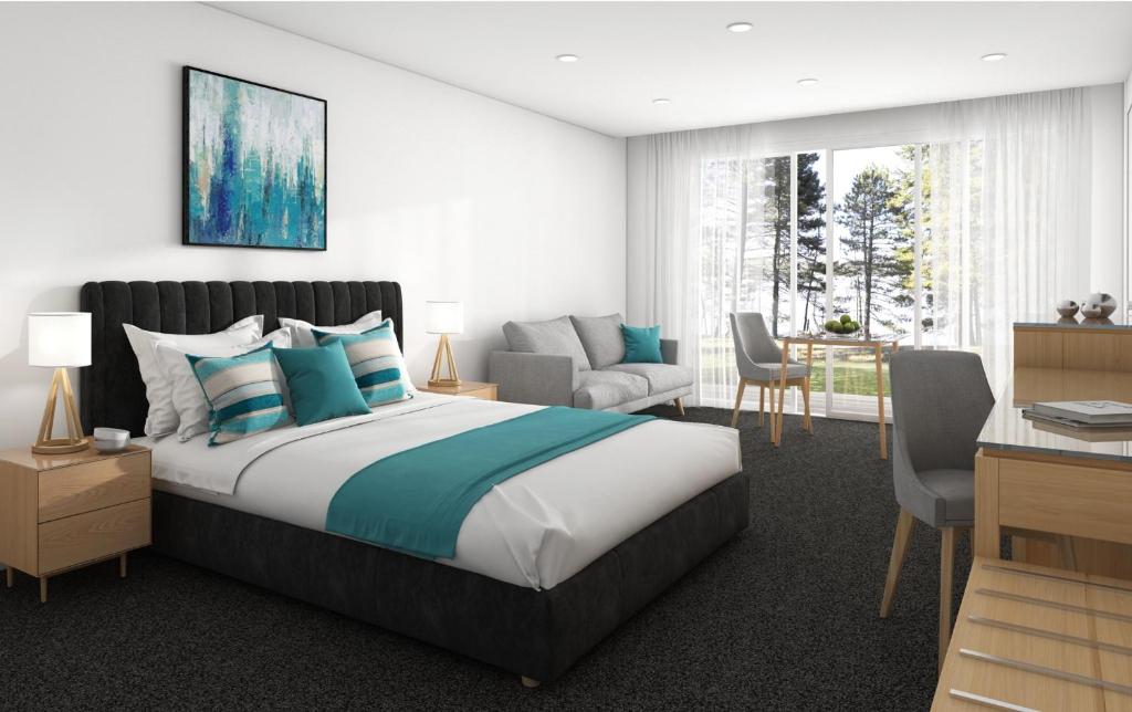 um quarto com uma cama grande, uma secretária e uma cadeira em Ensenada Motor Inn and Suites em Adelaide