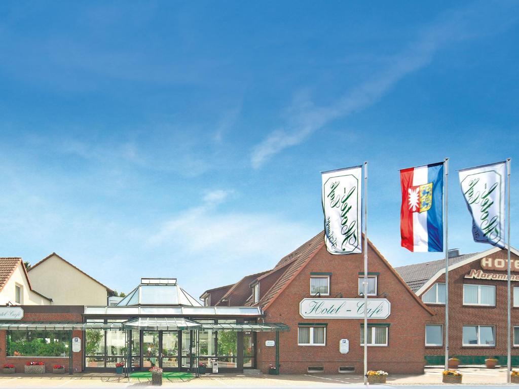 un bâtiment avec trois drapeaux au-dessus dans l'établissement Hotel-Café Kampe, à Norderstedt