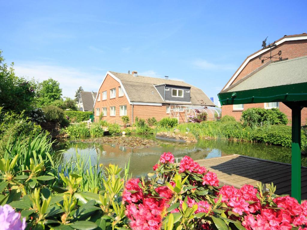 a garden with flowers and a house and a pond at Hotel Maromme in Norderstedt