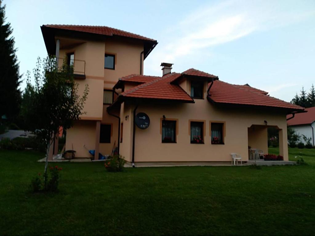 Una casa con un reloj en la parte delantera. en apartment jankovic en Zlatibor
