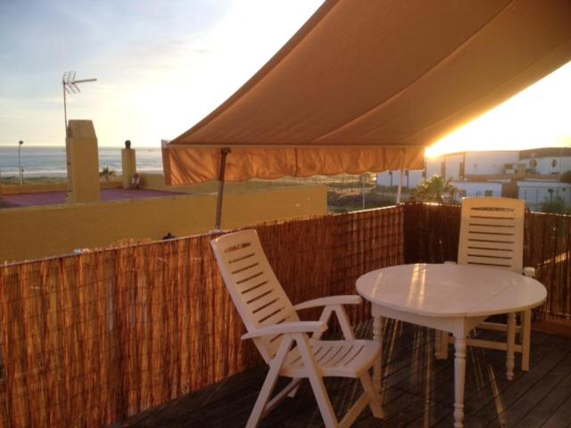 タリファにあるSea apartment views Tarifa wifiのビーチのあるパティオ(椅子2脚、テーブル1台付)