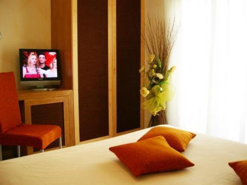 una camera con letto, TV e alevision di Villa Nettuno a San Menaio
