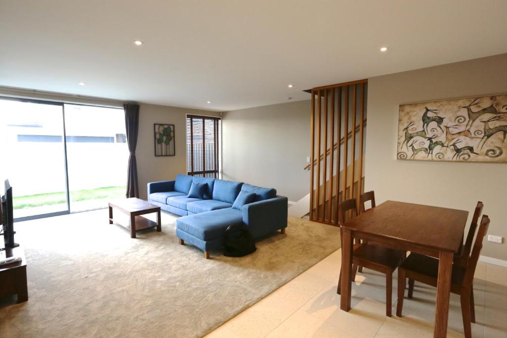 a living room with a blue couch and a table at Golden Sun Apartment -Two bedrooms, Three bedrooms in Christchurch