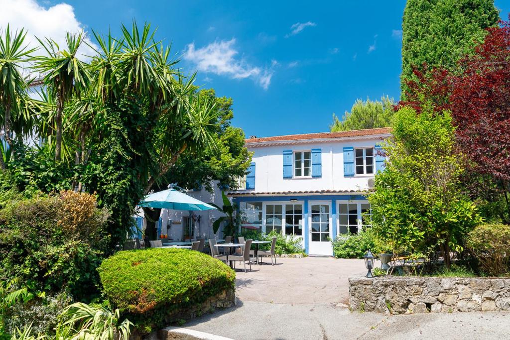 une grande maison blanche avec une terrasse et des arbres dans l'établissement Hôtel Les Liserons de Mougins, à Mougins