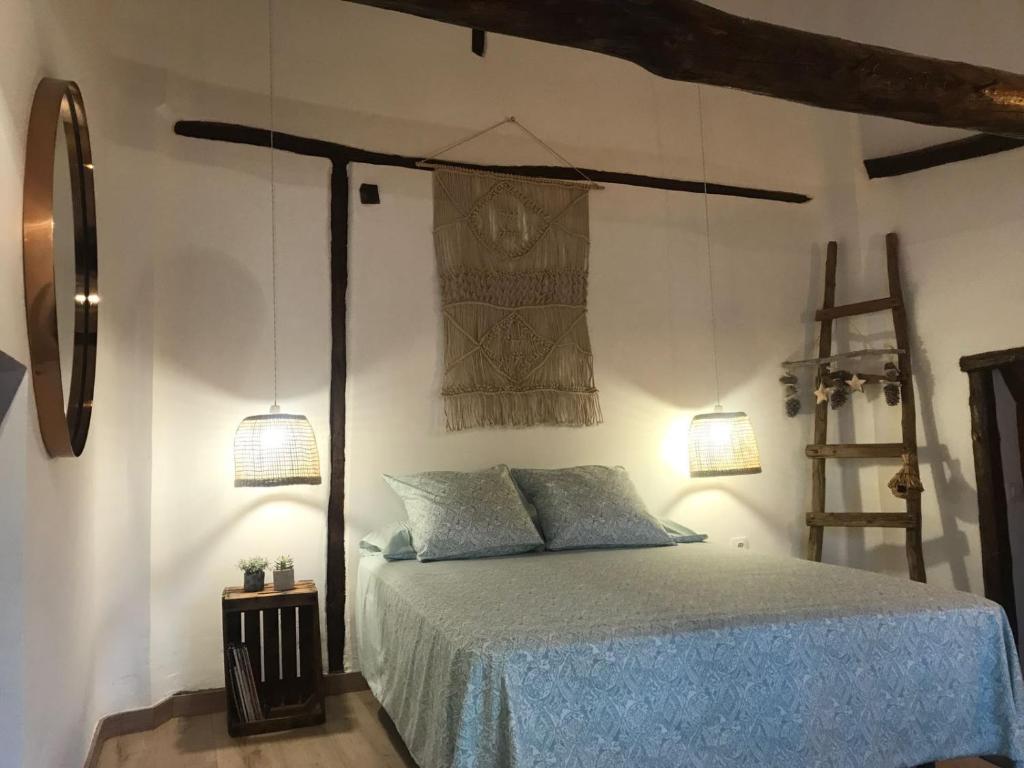a bedroom with a bed with blue sheets and two lights at Colores de Buendía in Buendía