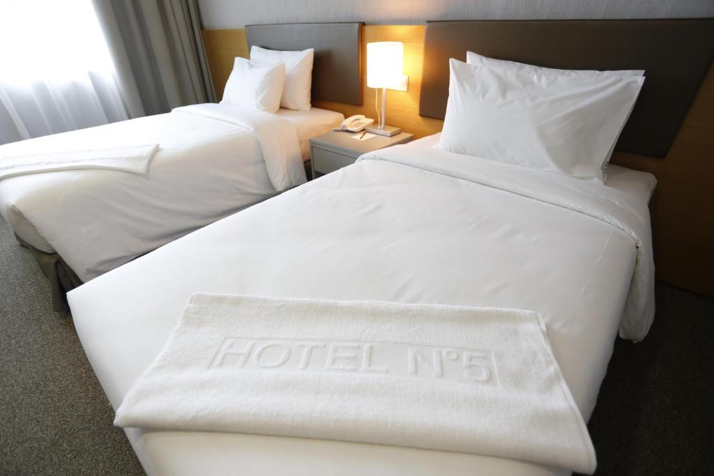 two beds in a hotel room with a hotel sign on them at Hotel N°5 in Kota Kinabalu