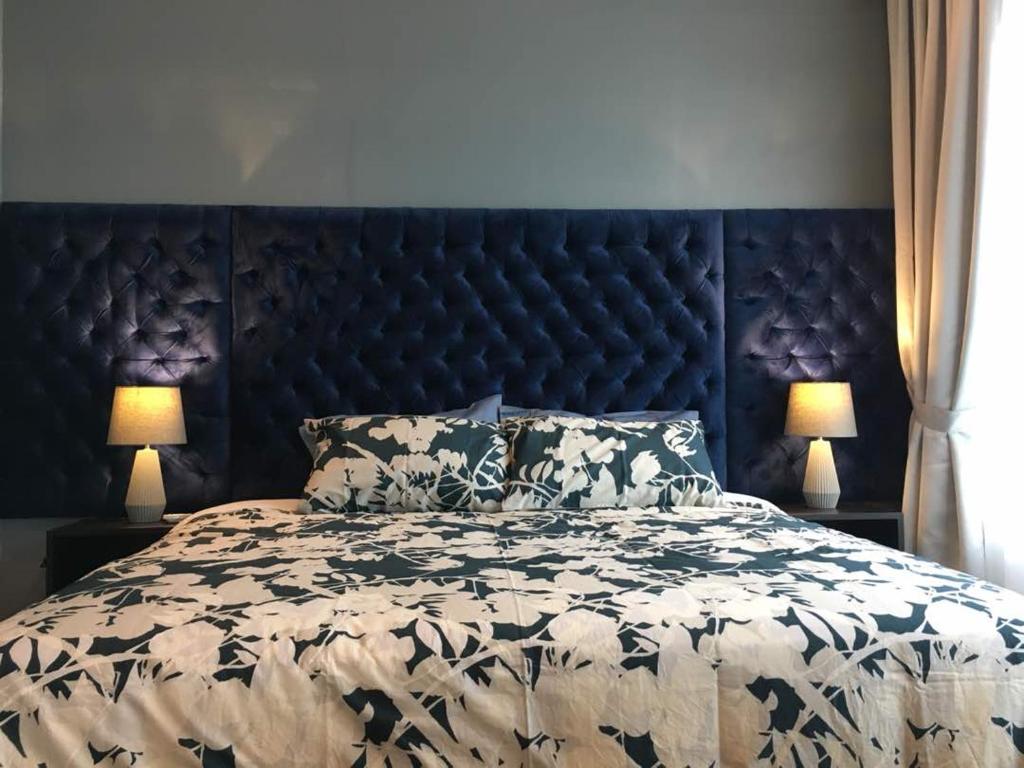 Palm Suite Ipoh Octagon في ايبوه: سرير كبير مع اللوح الأمامي الأسود ومصباحين