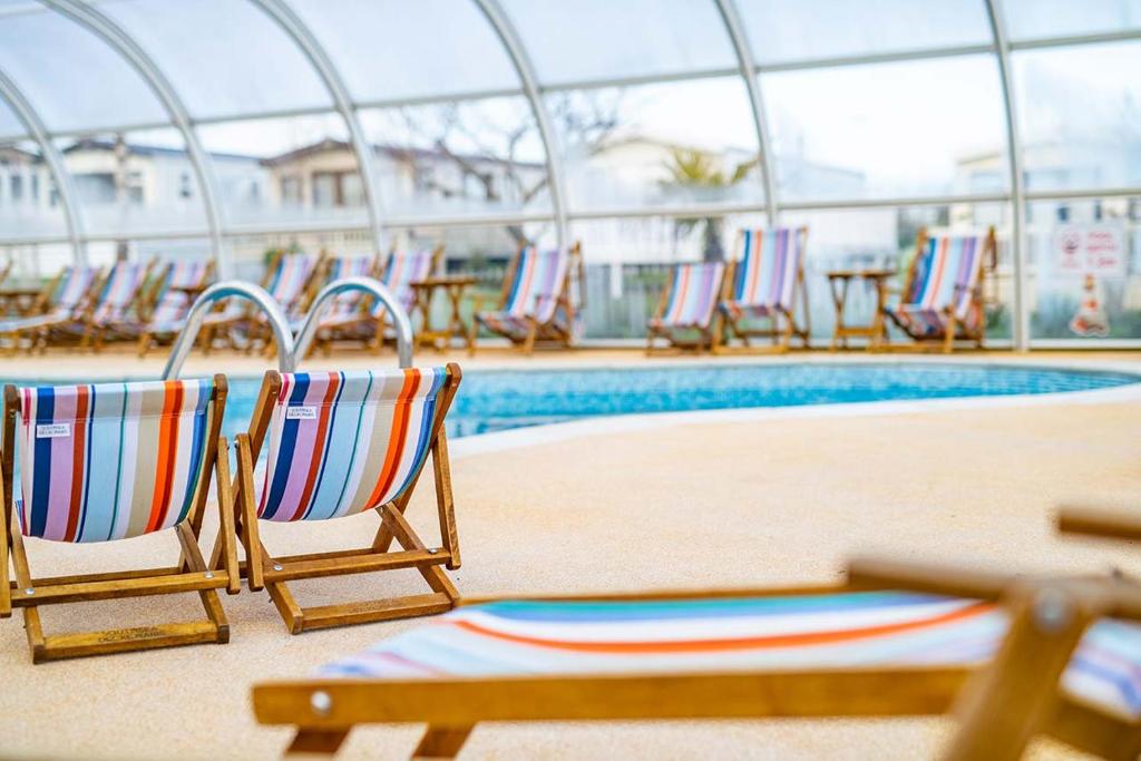 een groep stoelen naast een zwembad bij Mersea Island by Away Resorts in Colchester