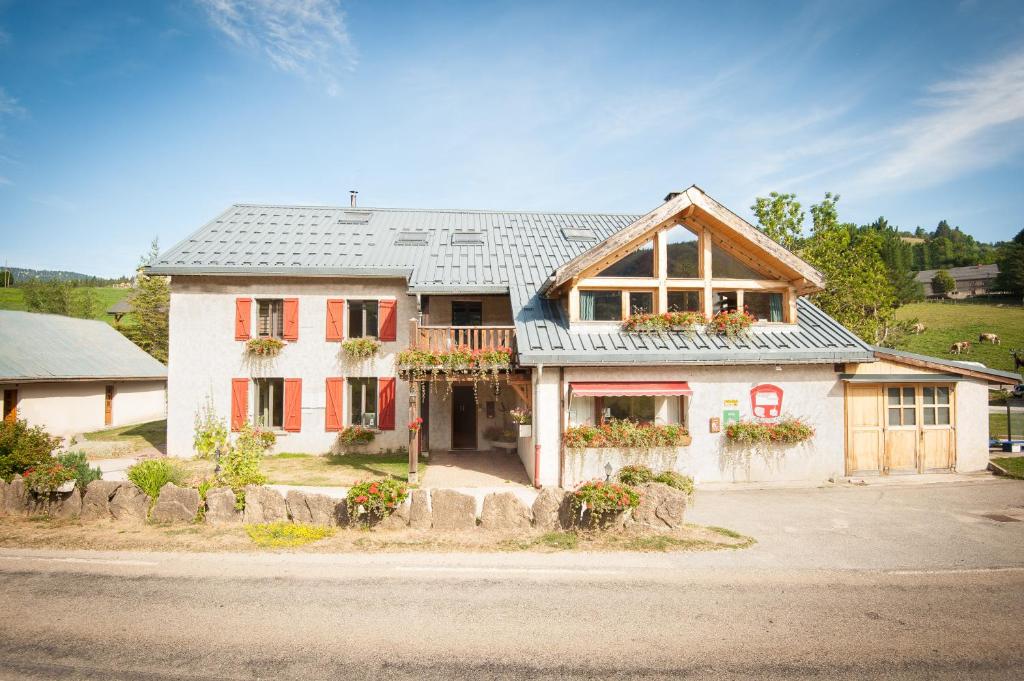 Una gran casa blanca con persianas rojas. en Arcanson, en Méaudre