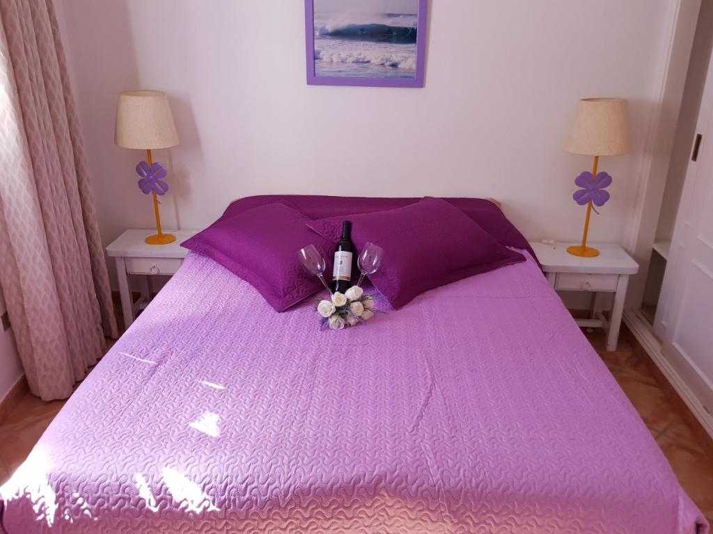 a purple bed with a bottle of wine and flowers on it at Vila Lavanda in Playa de las Americas