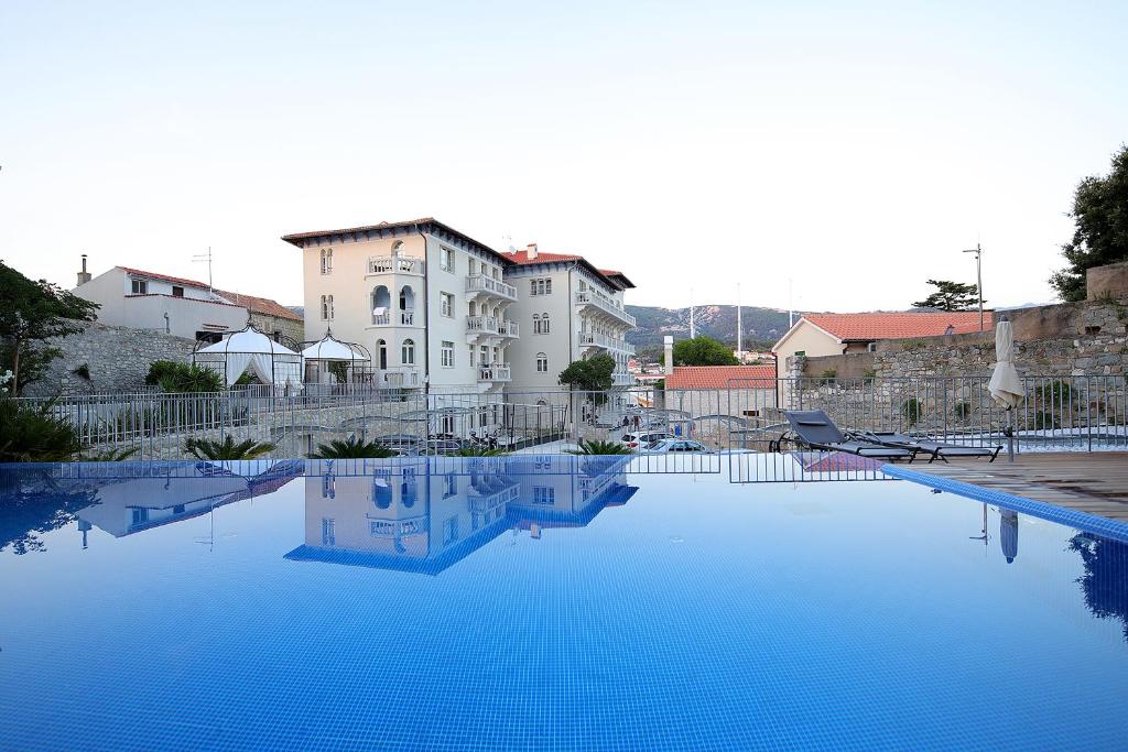 a large pool of blue water in front of a building at Arbiana Heritage Hotel in Rab