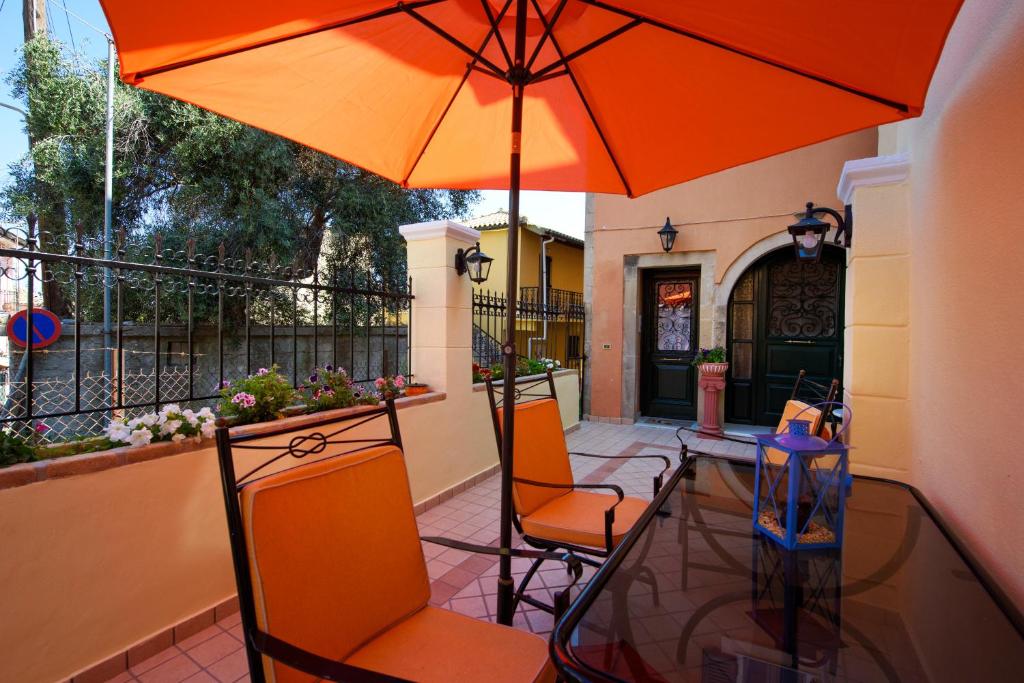 a patio with a glass table and an orange umbrella at The Old Mansion in Sinarádes