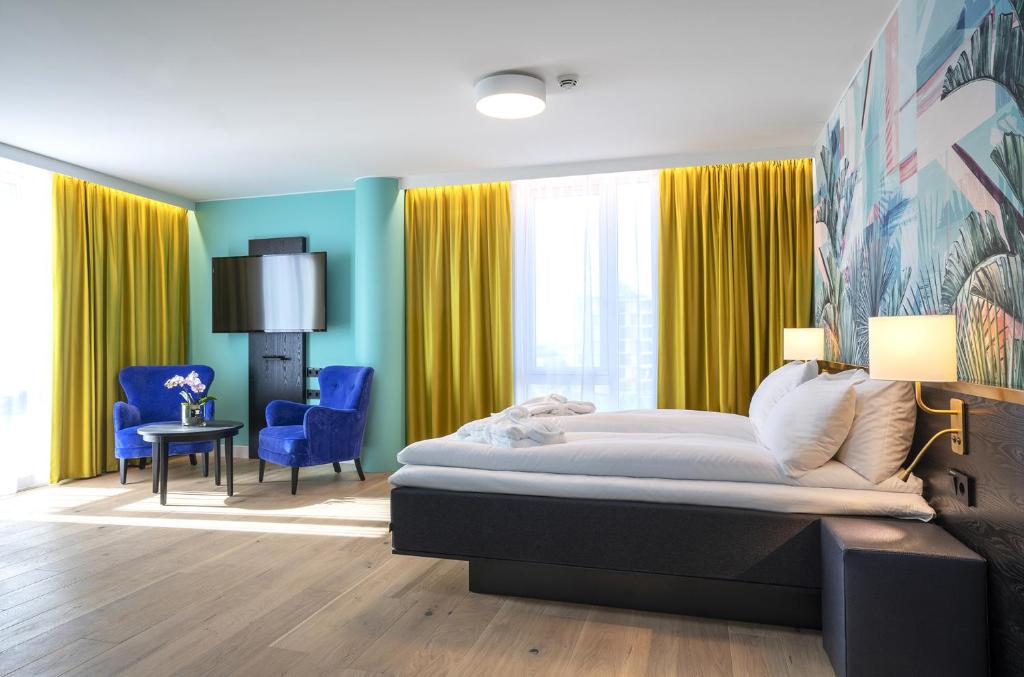 um quarto com uma cama grande e cortinas amarelas em Thon Hotel Storo em Oslo