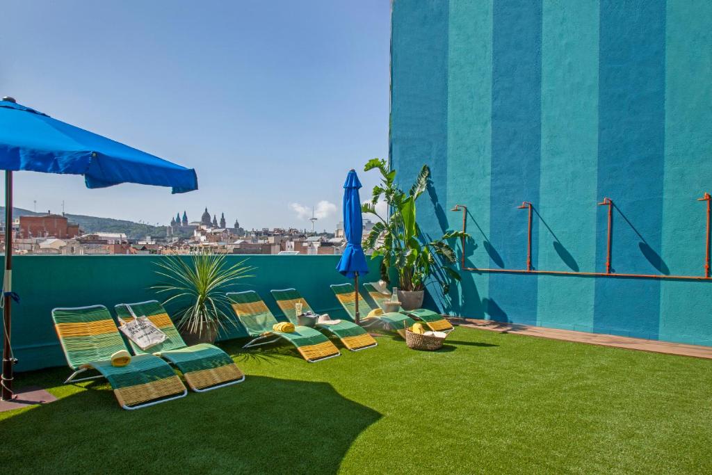 eine Terrasse mit Liegestühlen und Sonnenschirm auf dem Dach in der Unterkunft Chic & Basic Velvet in Barcelona