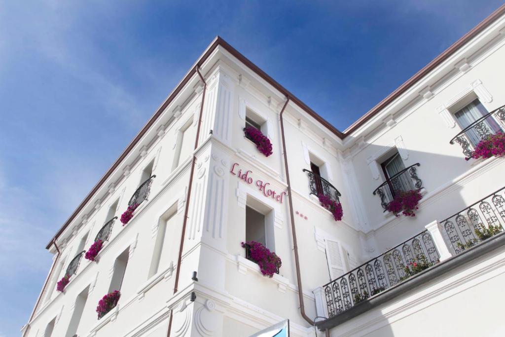 een wit gebouw met bloemen op de balkons bij Hotel Lido in Rimini
