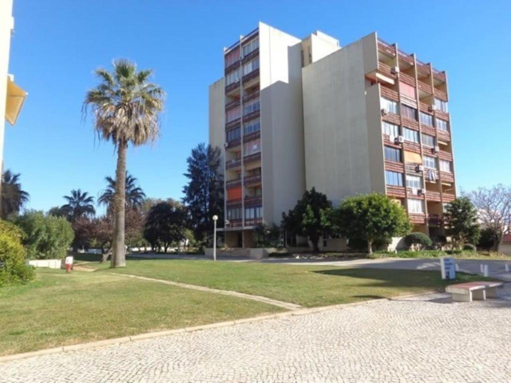 a building with a palm tree next to a park at Hello Chloé in Vilamoura