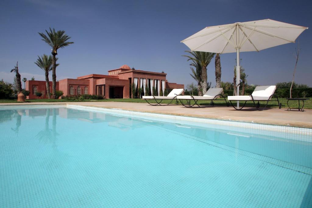 a swimming pool with two chairs and an umbrella at Dar Kamango in Marrakesh