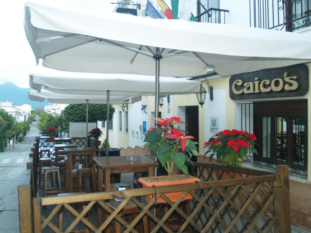 un restaurante al aire libre con mesas, sillas y sombrilla en Caico's, en Prado del Rey