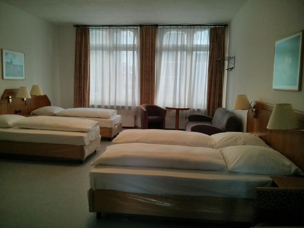 una habitación de hotel con 3 camas y una habitación con sillas en Willy Hotel Frankfurt, en Frankfurt