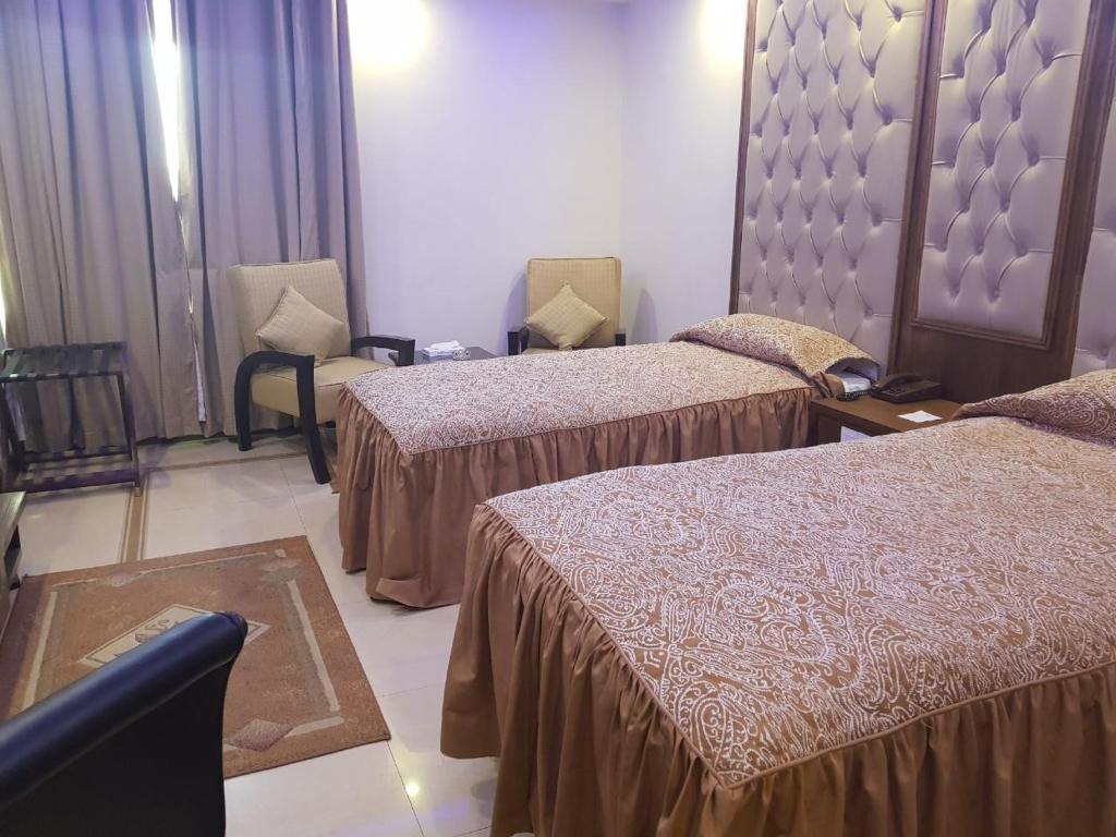 une chambre d'hôtel avec deux lits et deux chaises dans l'établissement Hotel Shalimar Rawalpindi, à Rawalpindi
