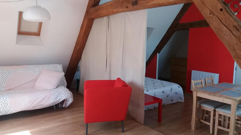 a bedroom with a red chair and a bed and a table at Le charme du château in Les Andelys