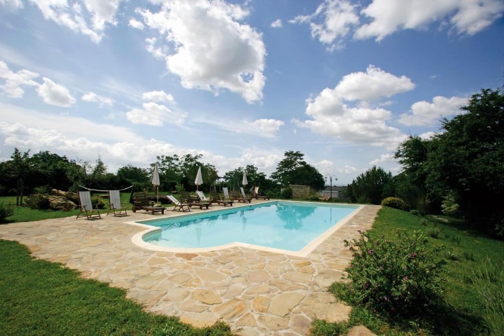 a large swimming pool with chairs and a blue sky at Agriturismo Le Calle in Cinigiano