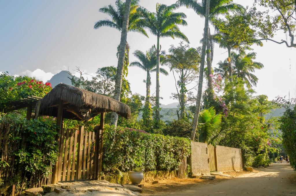 a fence with palm trees and a road at Casa e kitnet Morada Aguiar - casa in Abraão