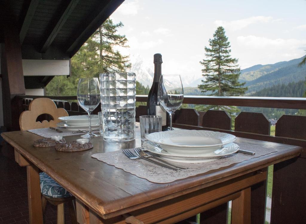 a table with plates and wine glasses on a balcony at I mughi - Cortina in Cortina dʼAmpezzo