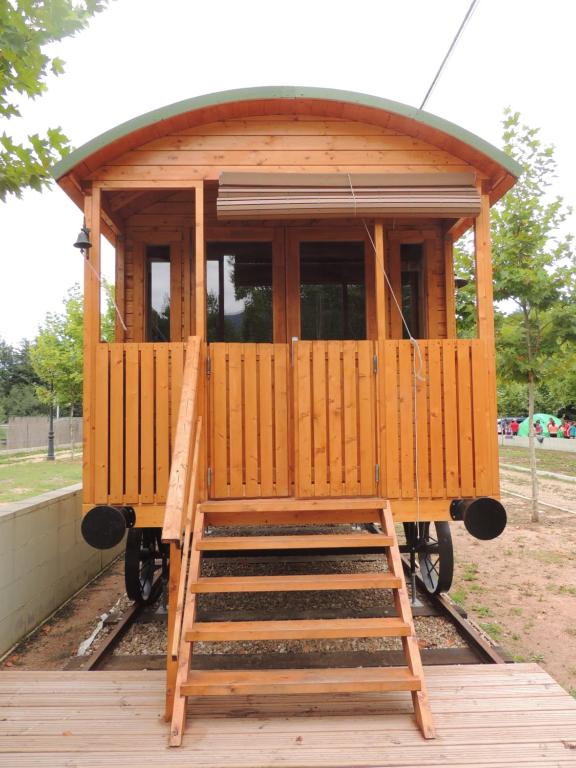 a wooden train car on a platform with a ladder at Càmping l'Alguer in Les Planes d'Hostoles