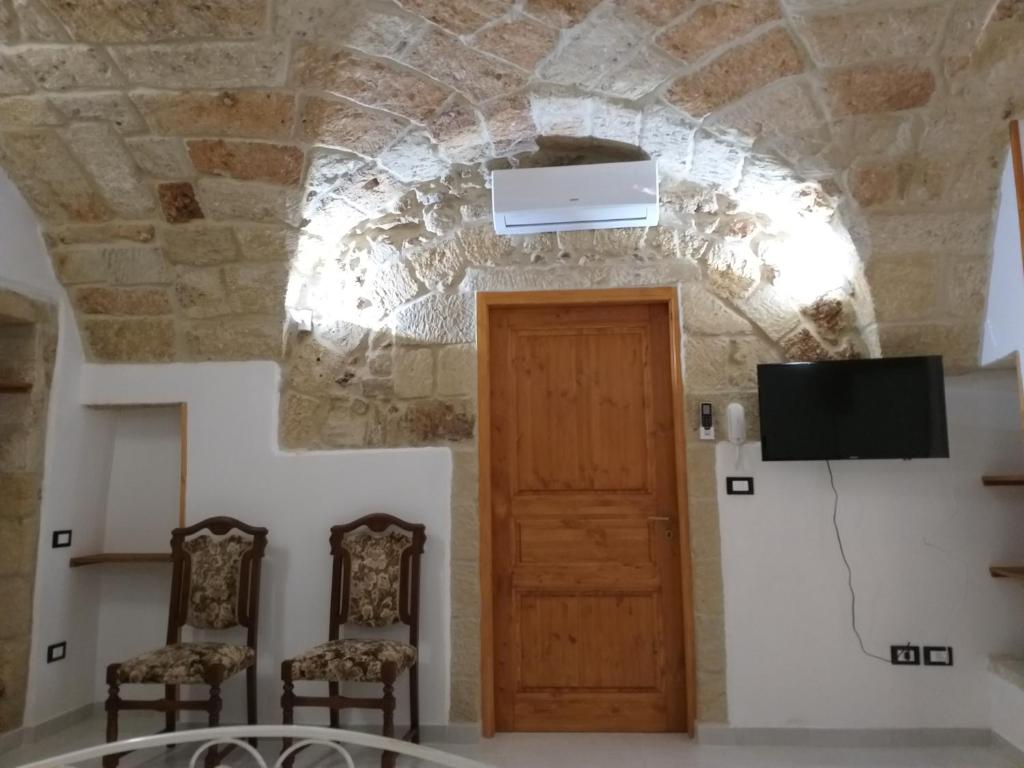 a room with a tv and two chairs and a door at Dimora Corte antica in Scorrano