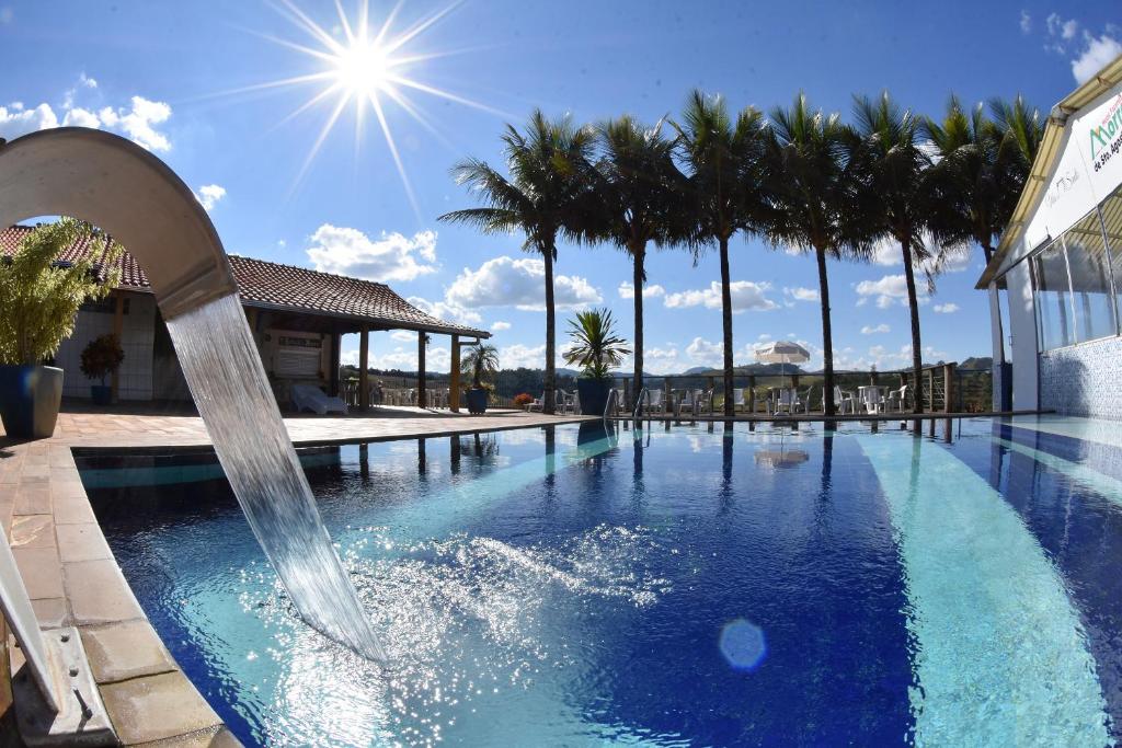 a swimming pool with a water slide and palm trees at Hotel Morro De Santo Agostinho in Serra Negra
