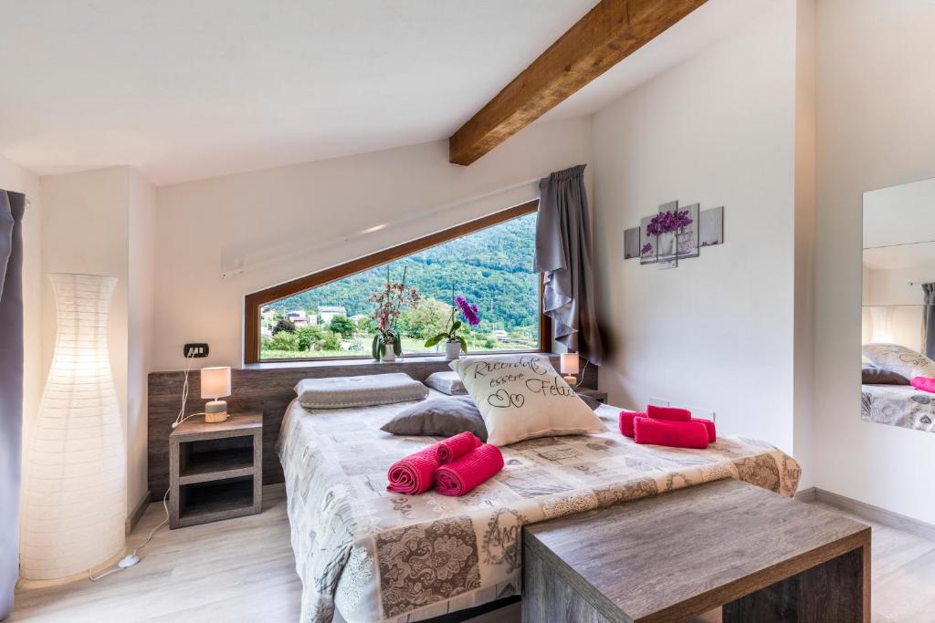a bedroom with a large window and a bed with red pillows at B&B Valtellina Mon Amour in Piateda