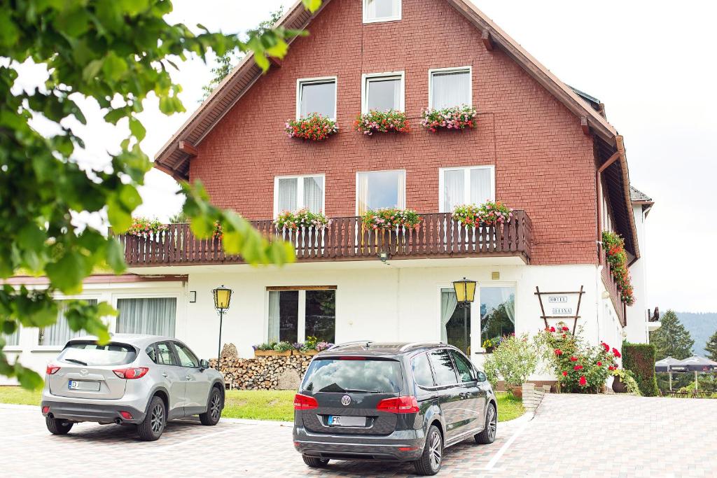 dwa samochody zaparkowane przed domem w obiekcie Hotel Diana w mieście Feldberg
