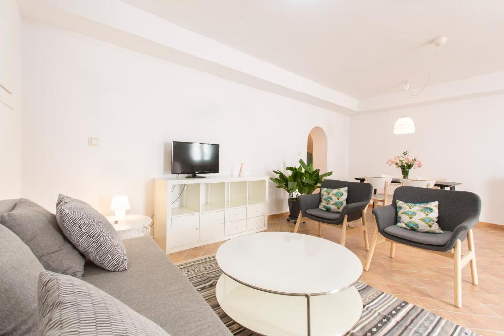 Una sala de estar con un sofá, una mesa y sillas. en Montes Claros 26, en Granada