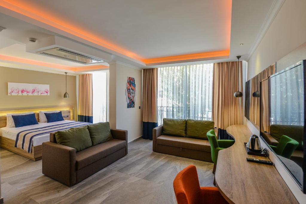 een slaapkamer met een bed, een bank en een tv bij Seyir Village Hotel in Oludeniz