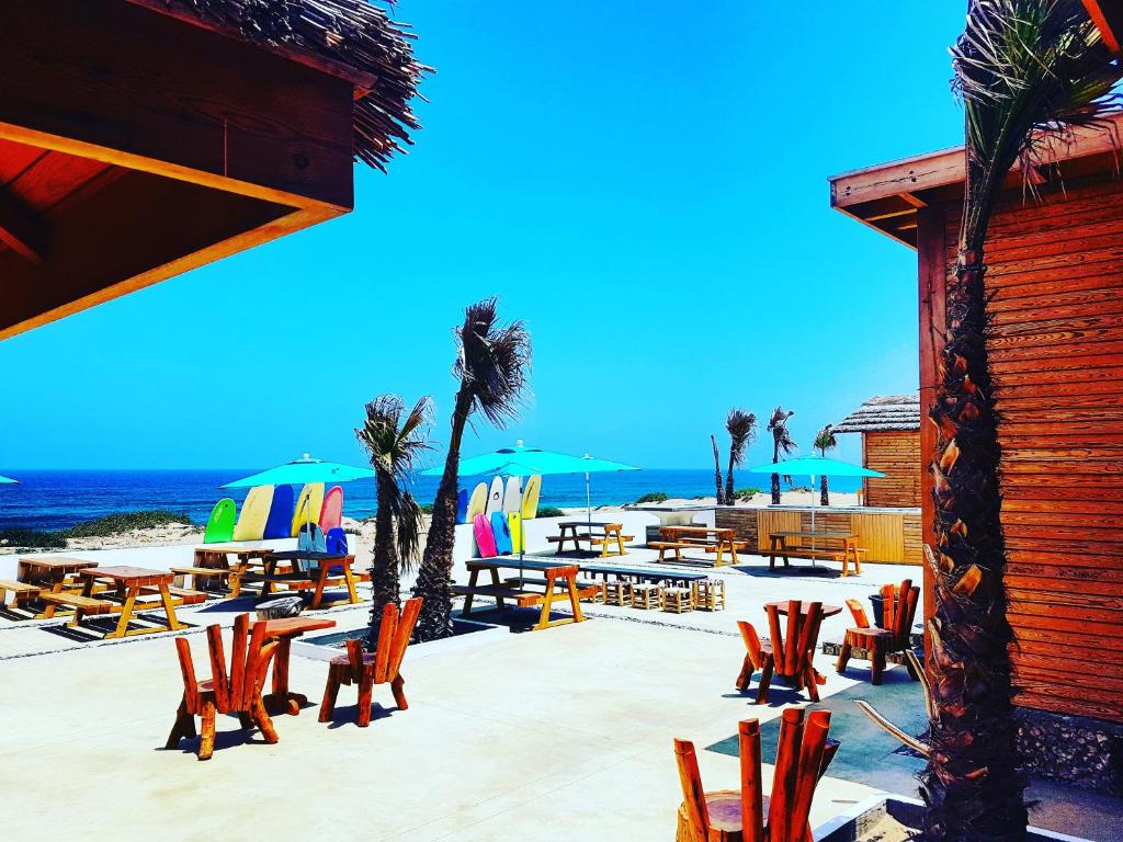 a group of chairs and tables on the beach at Greenwave Ecolodge in Mirleft