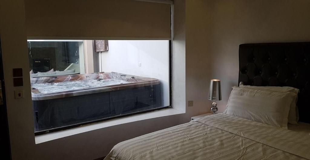 a bedroom with a bed and a window with a tub at Swarvoski Chalet in Riyadh