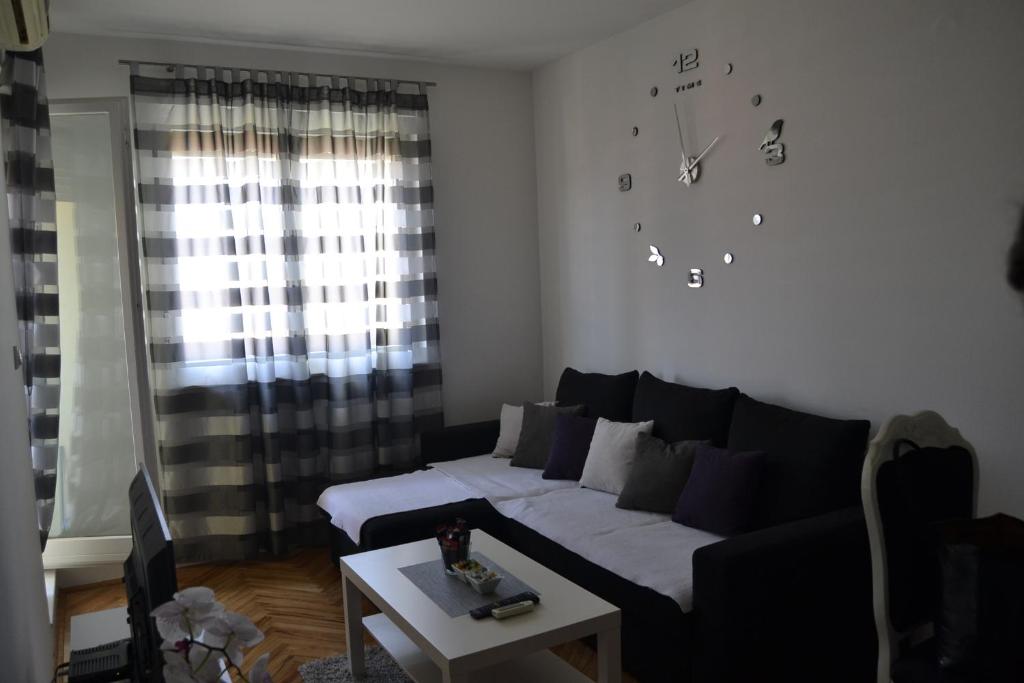 a living room with a couch and a clock on the wall at Apartman Rada in Bijeljina