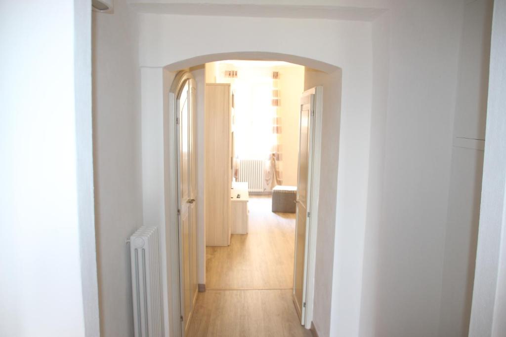 un corridoio con pareti bianche e pavimenti in legno e un corridoio con porta di Carolina Apartment a Rapolano Terme