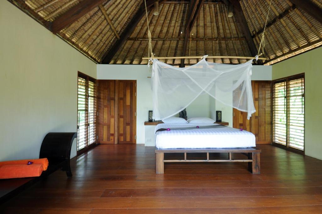 a bedroom with a bed with a mosquito net at Koh Yao Sunrise Villa in Ko Yao Noi