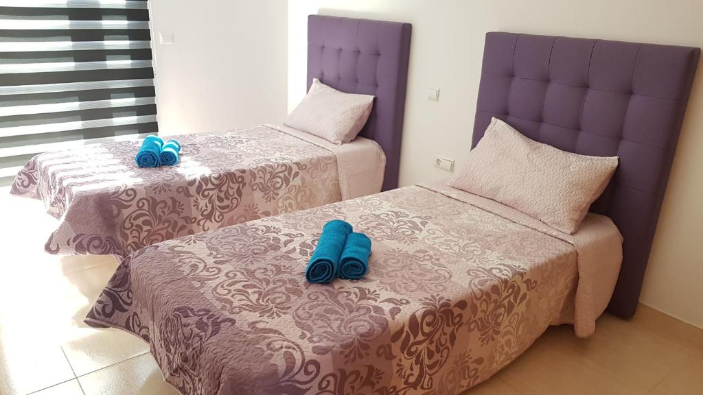 two beds with blue slippers on them in a bedroom at Exclusiva Vivienda en Cotillo in Cotillo