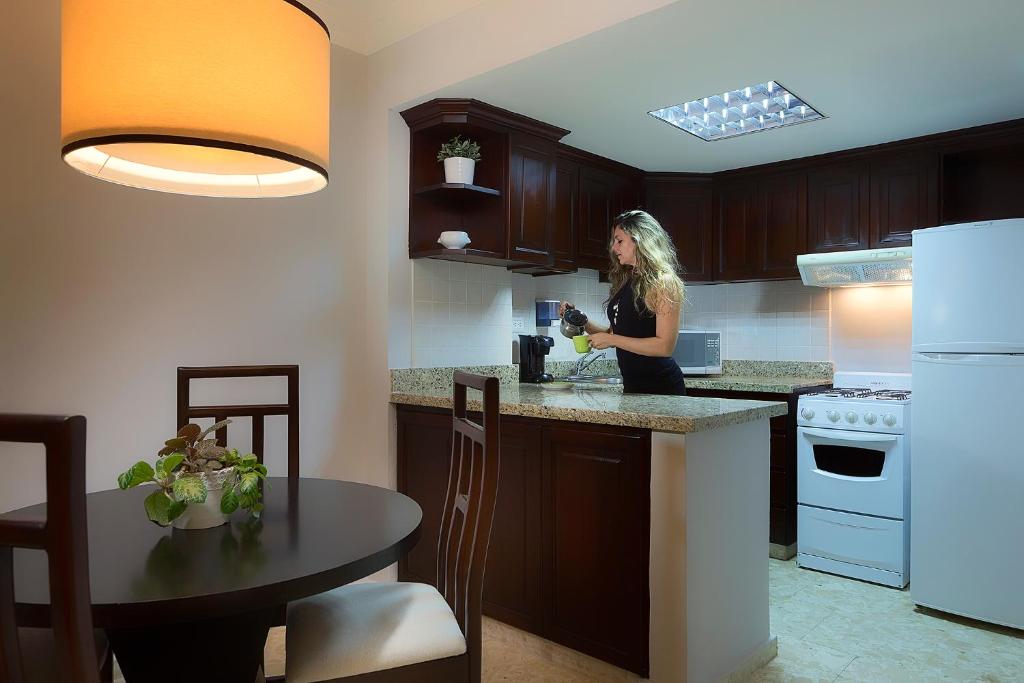 a woman standing at a kitchen counter drinking a drink at Plaza Florida Suites in Santo Domingo