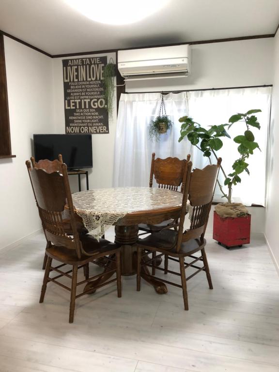 una mesa de comedor con 2 sillas y una planta en Amami Weekly House Nico nico, en Amami