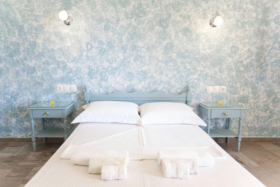 1 Schlafzimmer mit einem weißen Bett und 2 blauen Tischen in der Unterkunft kyma studios in Livadion