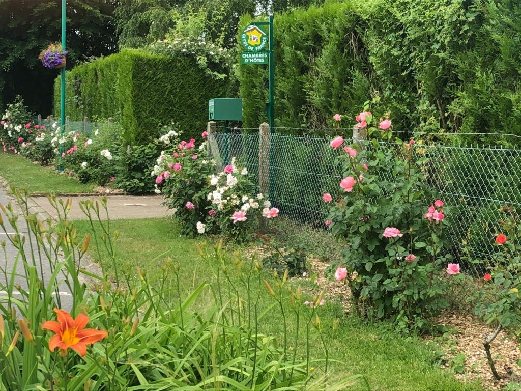 un jardín con flores rosas y blancas y una valla en Petit Manoir du Bosc, en La Neuville-du-Bosc