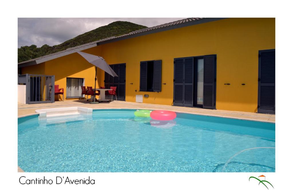 uma piscina em frente a uma casa amarela em Cantinho D'Avenida em Velas
